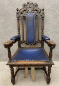 A late 19th/early 20th century carved oak throne or hall chair, the back being surmounted by a