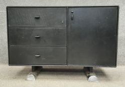A mid-century leather clad sideboard/credenza having three drawers and a cabinet door on cylindrical