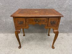 A Georgian style walnut kneehole lowboy with a an inlaid and crossbanded top above three frieze
