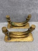 A pair of early 20th century patinated giltwood coffee table bases each having two carved faux horns