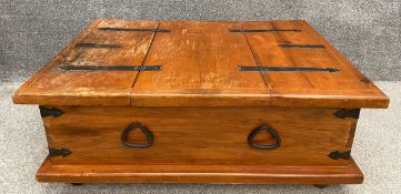 A mid to late 20th century teak low table with two compartments under hinged lids with iron strap