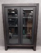 A contemporary ebonised display cabinet with a mahogany interior having three shelves behind two