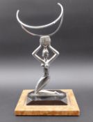 An Art Deco stylised figural chrome lady bottle holder/stand on a square stepped ebonised and marble