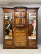 A large late 19th century rosewood compactum wardrobe in three sections having a moulded cornice