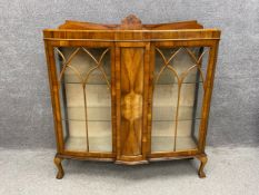 A mid century Art Deco style walnut breakfront display cabinet having a raised and shaped gallery