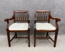 A pair of 19th century style teak carver elbow chairs with slatted backs and scrolling armrests on