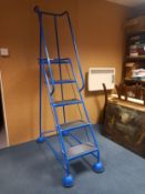 A Steptek narrow safety warehouse or library ladder with five steps on multidirectional casters.
