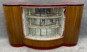 A mid century teak home bar in the Art Deco style with mirrored doors to the back opening to a bowed