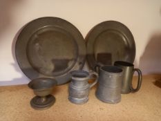 A colection of 18th century and later pewter to include two plates, three tankards and a goblet. All