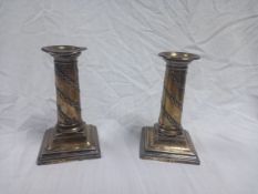 A pair of hallmarked silver candlesticks of classical column form with foliate decoration, on shaped