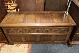 A VINTAGE OAK CARVED PANELLED COFFER W 122 CM