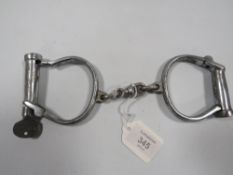 A SET OF VINTAGE HANDCUFFS WITH KEY