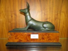 A BRONZE TYPE MODEL OF AN EGYPTIAN STYLE DOG ON A WALNUT EFFECT PLINTH