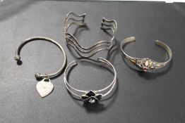 A SELECTION OF FOUR SILVER AND WHITE METAL BANGLES A/F