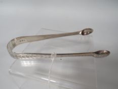 A PAIR OF GEORGIAN HALLMARKED SILVER BRIGHT CUT SUGAR TONGS