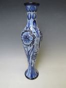 A MOORCROFT POTTERY FLORIAN SLENDER VASE, with tubelined floral sprays on contrasting blue ground,