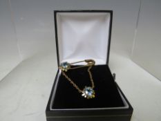 A HALLMARKED 9CT GOLD UNUSUAL GEMSET BROOCH, in the form of a safety pin with two floral