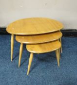 AN ERCOL LIGHT ELM 'PEBBLES' NEST OF THREE TABLES