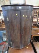 AN ANTIQUE OAK BOWED HANGING CORNER CUPBOARD