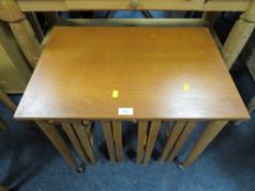 A MID CENTURY TEAK NEST OF TABLES ON CASTORS