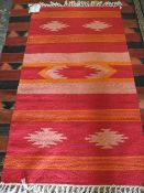 A RED / ORANGE WOOLLEN RUG - 90 X 150 CM