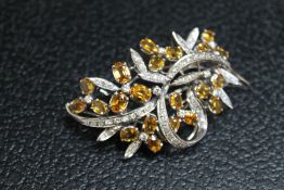 AN UNMARKED WHITE METAL GEM SET BROOCH, set with twenty one citrine style stones and diamonds,