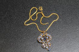 AN ORNATE SAPPHIRE PENDANT, set in unmarked yellow metal and on a similar chain with simple s link