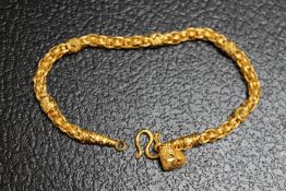 AN ORNATE YELLOW METAL BRACELET WITH HEART CHARM, stamped 96.5%, with simple S link fastening,