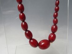 A CHERRY RED FATURAN AMBER GRADUATED OVAL BEAD NECKLACE, approx L 59 cm, approx weight 40 g