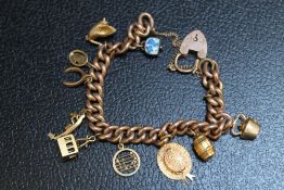 A 9CT ROSE GOLD CHARM BRACELET ADORNED WITH TEN ASSORTED CHARMS, approx weight 31.9g
