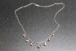 A WHITE METAL NECKLACE SET WITH SEVEN TEARDROP SHAPED IRIDESCENT STONES, possibly 'Star Sapphires',