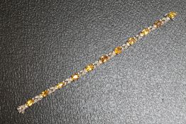 AN UNMARKED WHITE METAL GEM SET BRACELET, set with eleven citrine style stones and diamonds on a box