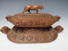 A LARGE BLACK FOREST CARVED LIDDED DISH ON A CARVED BASE, the handle in the shape if a wild