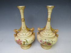 A PAIR OF ROYAL WORCESTER BLUSH IVORY TWIN HANDLED VASES, decorated with flowers and rams head