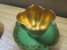 AN ANTIQUE COALPORT DEMITASSE QUATREFOIL GREEN AND GOLD CUP AND SAUCER