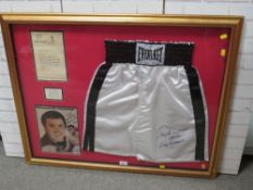 A PAIR OF FRAMED BOXING SHORTS AND A PICUTRE OF MUHAMMAD ALI, both signed by trainer Angelo