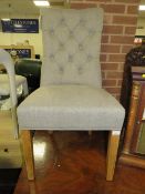 A modern grey upholstered button backed dining chair