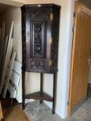 An antique oak heavily carved corner cupboard on a later stand, cupboard H 113 cm