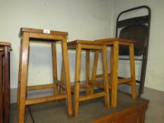 Three mid century wooden stools together with an industrial folding style chair