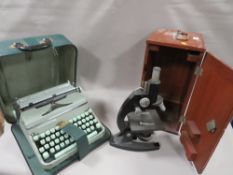A VINTAGE WOODEN CASED MICROSCOPE WITH A PORTABLE TYPEWRITTER