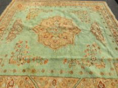 A large late 19th/early 20th century woollen rug on a mainly green ground, approximately 295 x 272