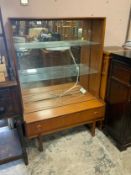 A mid-century teak glazed bookcase with single draw below W 91 cm