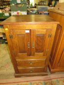 A small oak two door cabinet with two drawers below
