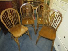 A set of four wheel back dining chairs