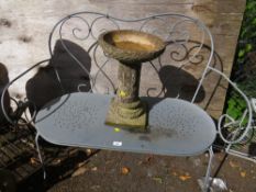 A modern steel garden bench and a concrete bird bath