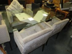 A modern glass topped dining table together with four armchairs