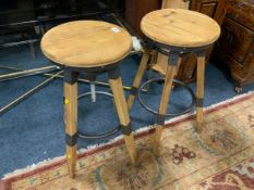 A pair of modern swivel adjustable wooden stools with cast metal fittings