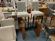 A modern glass top rectangular dining table with two upholstered chairs