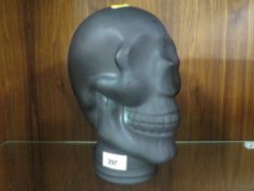 A black glass head in the form of a skull