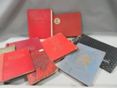 A tray of vintage empty cigarette card and stamp albums